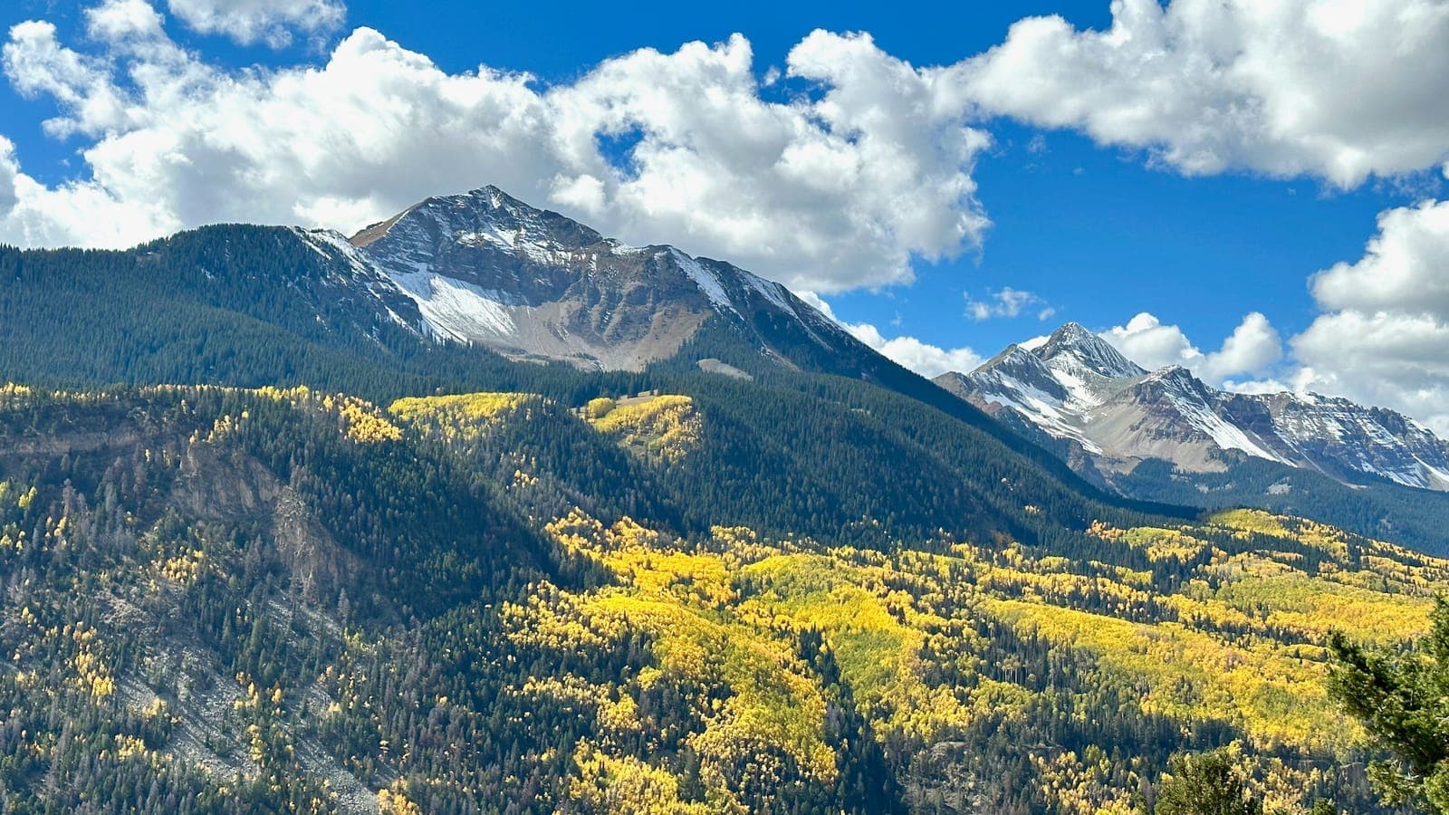 A moving truck on I-25 with the Front Range and snow-capped Rocky Mountains behind Colorado Springs near a military installation