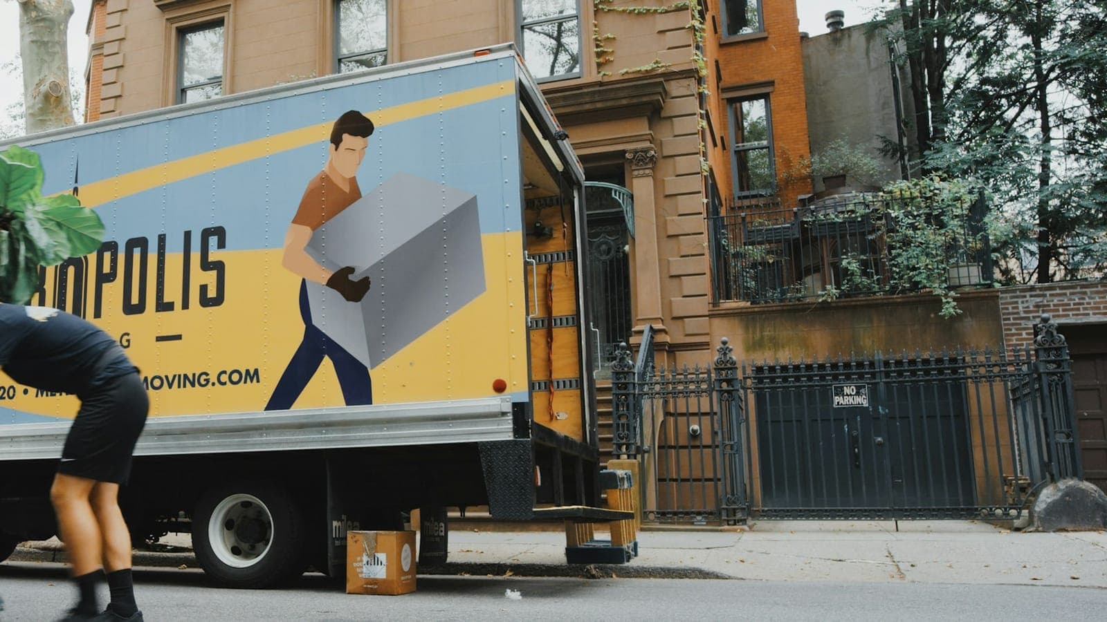 Movers carrying furniture into a Denver home on a sunny summer day with the Front Range in the background