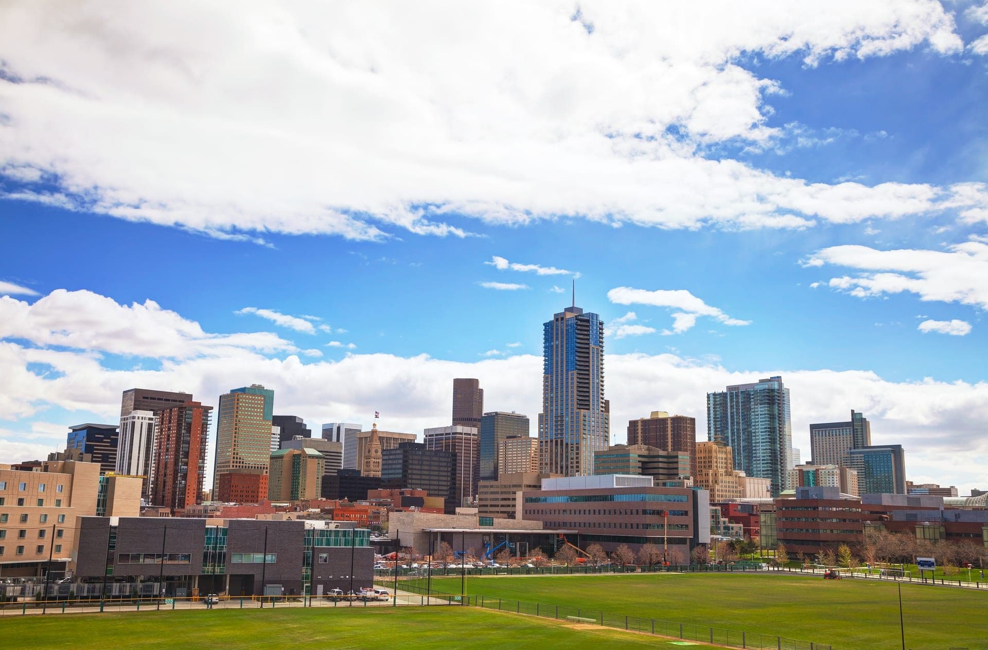 Denver skyline in daylight with the Rocky Mountains on the horizon